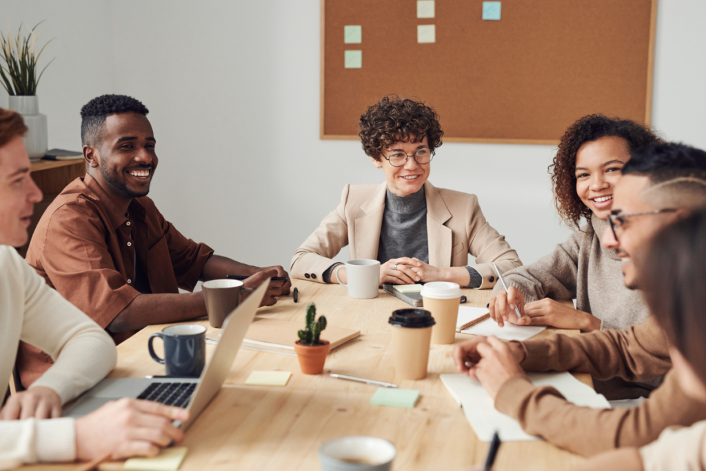 Diverse group of employees are happily discussing a topic around a conference table.