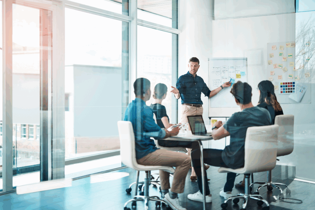 group of colleagues having a planning meeting with a leader at a whiteboard